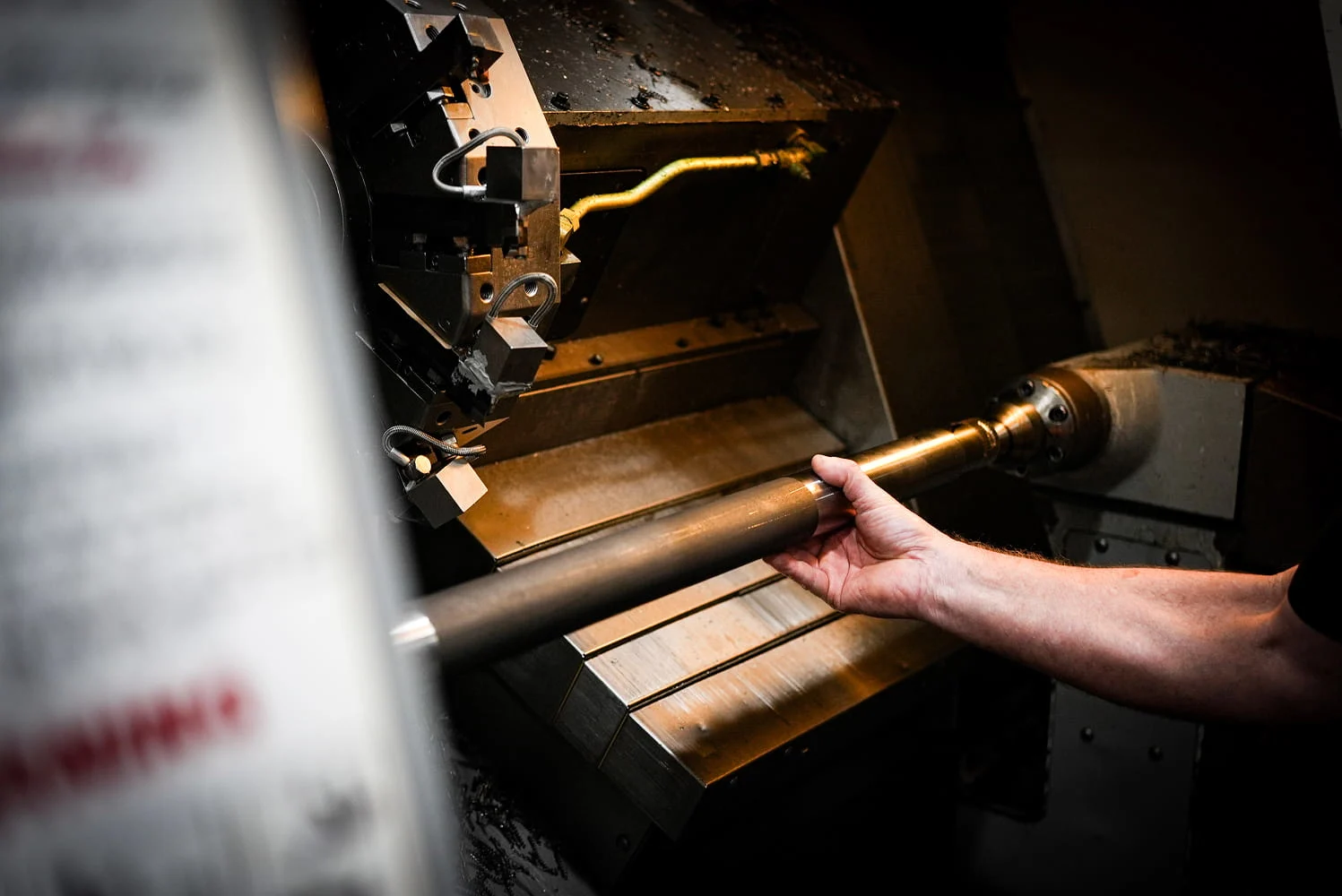 Machinist loading brass bar stock into CNC lathe chuck for turning operation