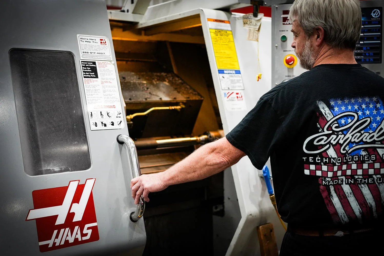 ETG technician opening Haas CNC lathe enclosure to inspect workpiece