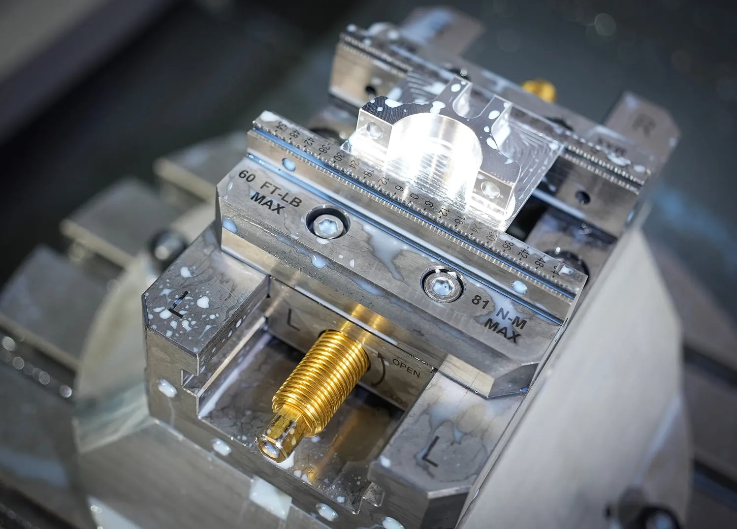 Aluminum workpiece and brass threaded component secured in precision vise during CNC milling