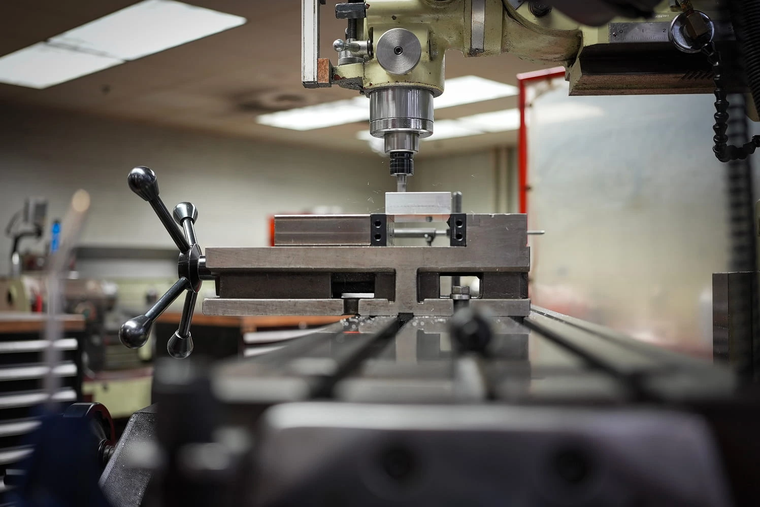 Vertical milling machine spindle positioned over aluminum workpiece in precision vise