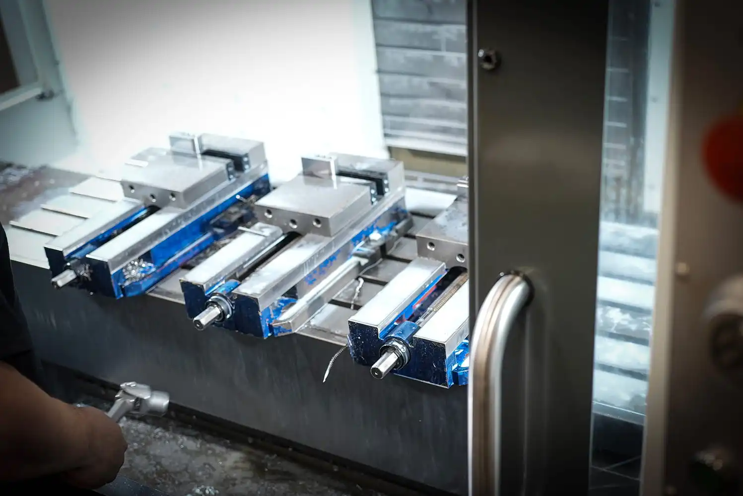 Aluminum workpieces secured in multiple precision vises inside CNC machining center