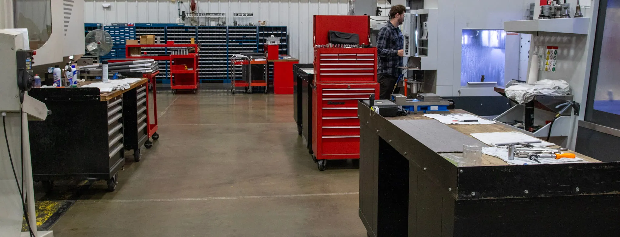 ETG machine shop floor with machinist working alongside CNC equipment and tool storage
